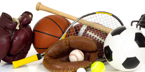 Variety of sports equipment on white background with copy space, items inlcude boxing gloves, a basketball, a soccer ball, a football, a baseball bat, a catcher's mitt or glove, a tennis racket and ball, a golf ball, and a baseball catchers mask